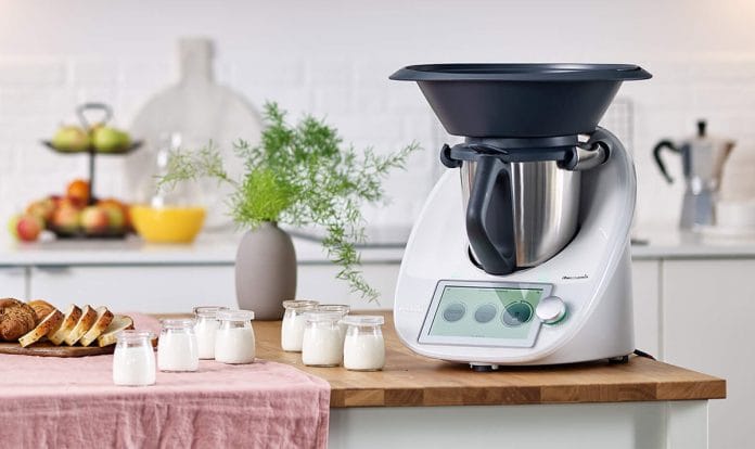 thermomix TM6 sur un plan de travail dans une cuisine avec des yaourts préparés.