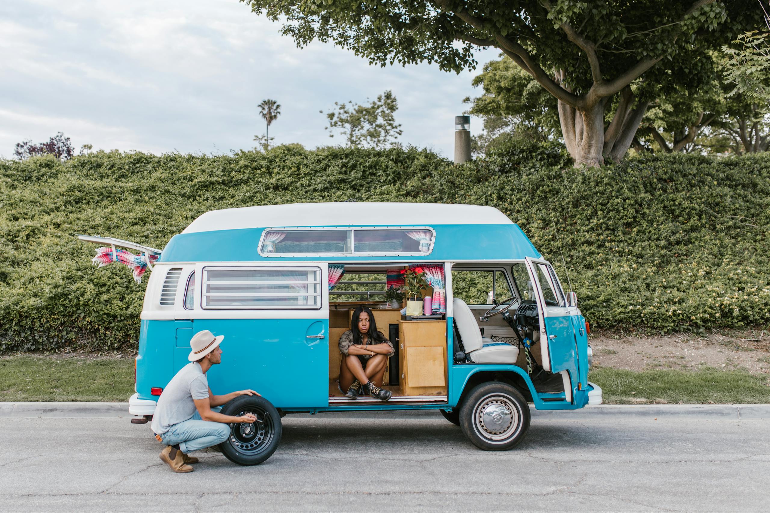 A couple enjoying a road trip with their vintage campervan, capturing a moment of rest and adventure.