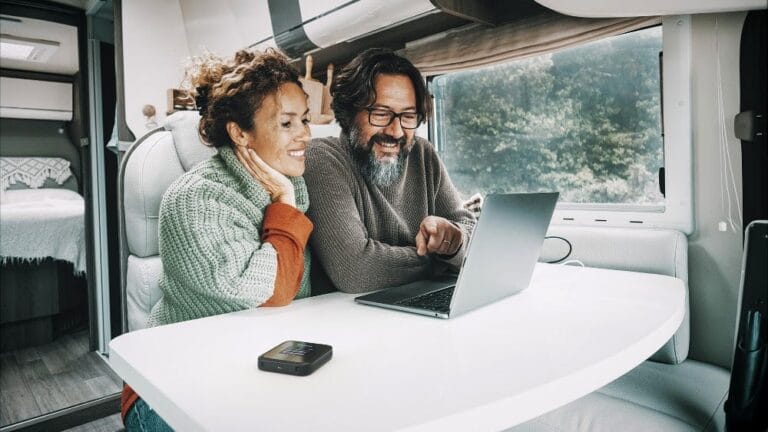un couple utilise un routeur mobile 5G en vacances dans son camping car