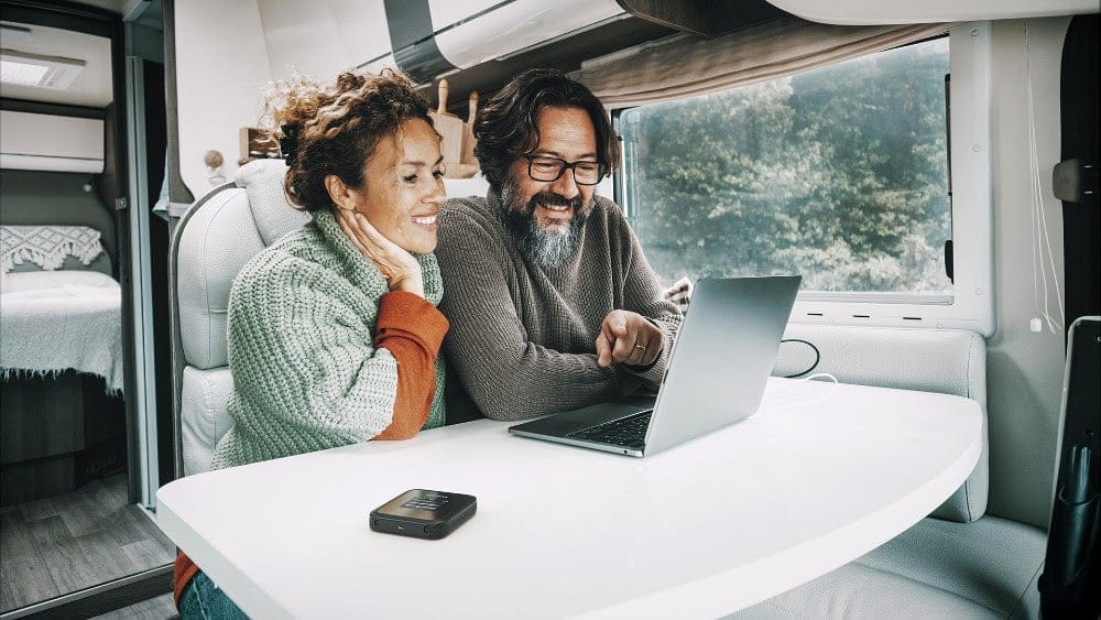 un couple utilise un routeur mobile 5G en vacances dans son camping car