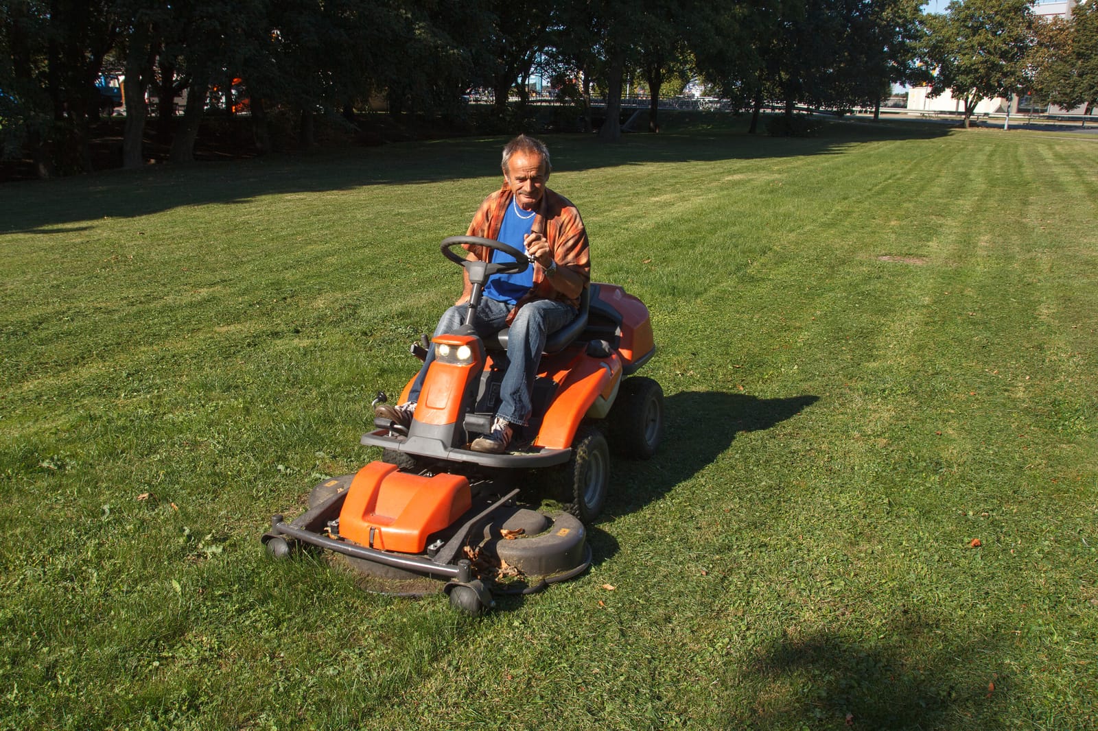 un homme tond la pelouse sur son tracteur tondeuse