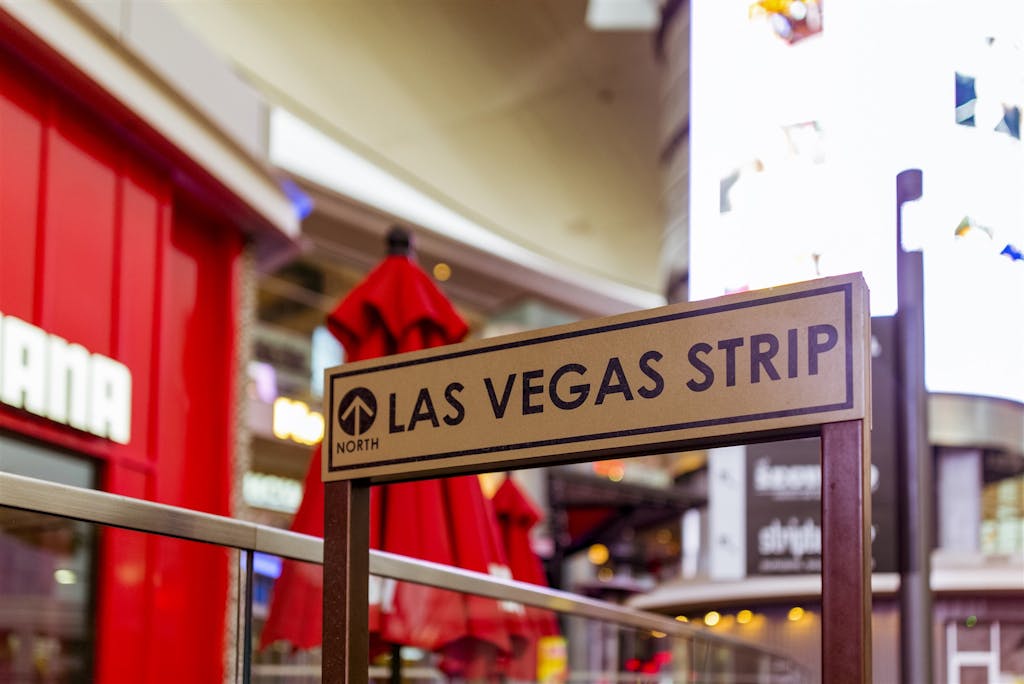 Iconic Las Vegas Strip sign with vibrant city life background.