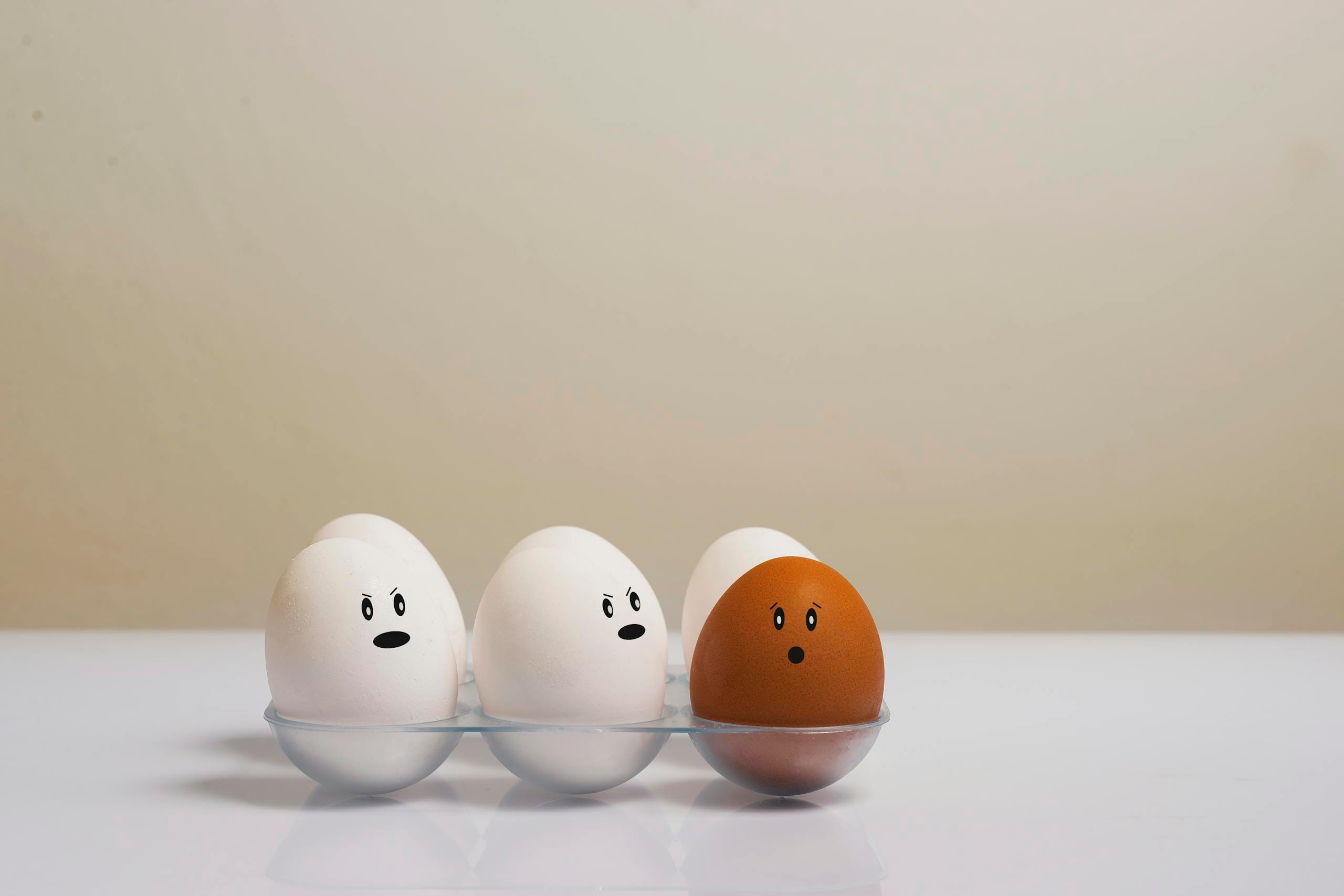A creative depiction of eggs with facial expressions in a tray, symbolizing diversity.