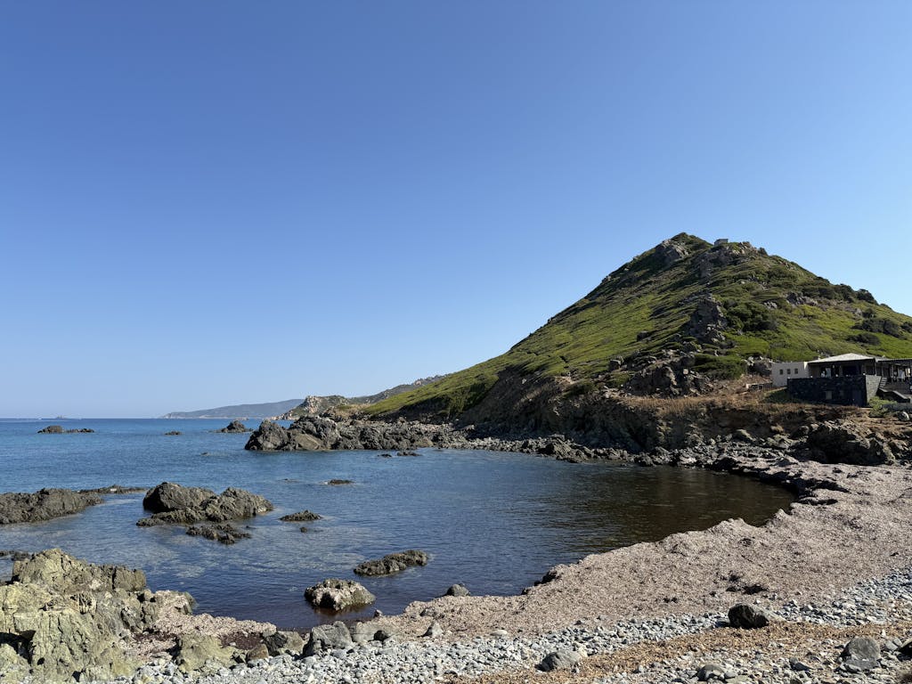 Breathtaking coastal landscape with rocky shores and a lush hill in Ajaccio, Corsica, France.